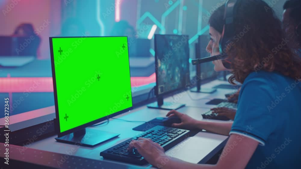 Pro Girl Plays Computer Video Game with Green Screen Display on a Championship, Talking into Headset. Diverse Esport Team of Pro Gamers Play in Mock-up Video Game. Cyber Games Arena.Over The Shoulder Pro Girl Plays Computer Video Game with Green Screen Display on a Championship, Talking into Headset. Diverse Esport Team of Pro Gamers Play in Mock-up Video Game. Cyber Games Arena.Over The Shoulder