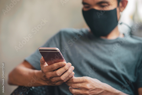 Close up hand holding mobile smartphone,man a wearing face mask in cafe