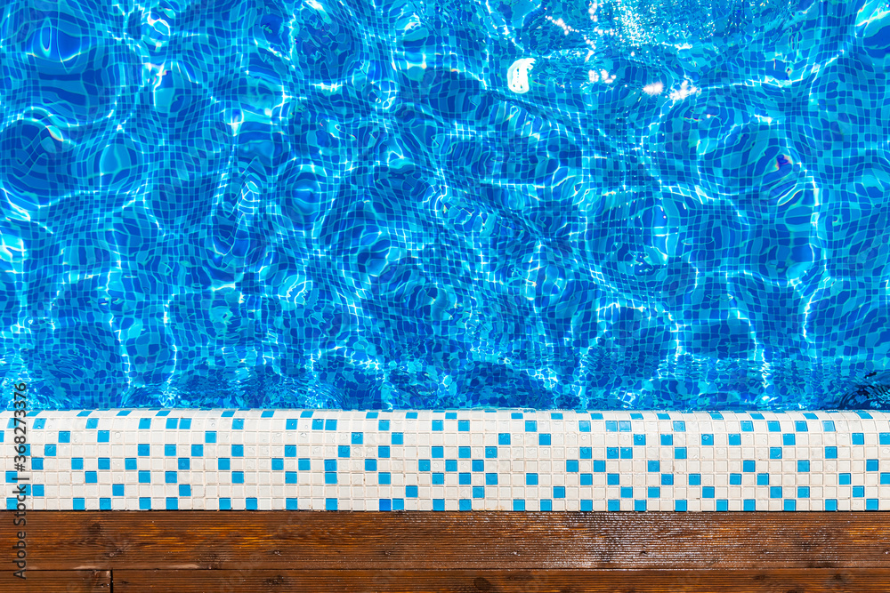 Top view blue swimming pool with teak wood flooring stripes sunlight