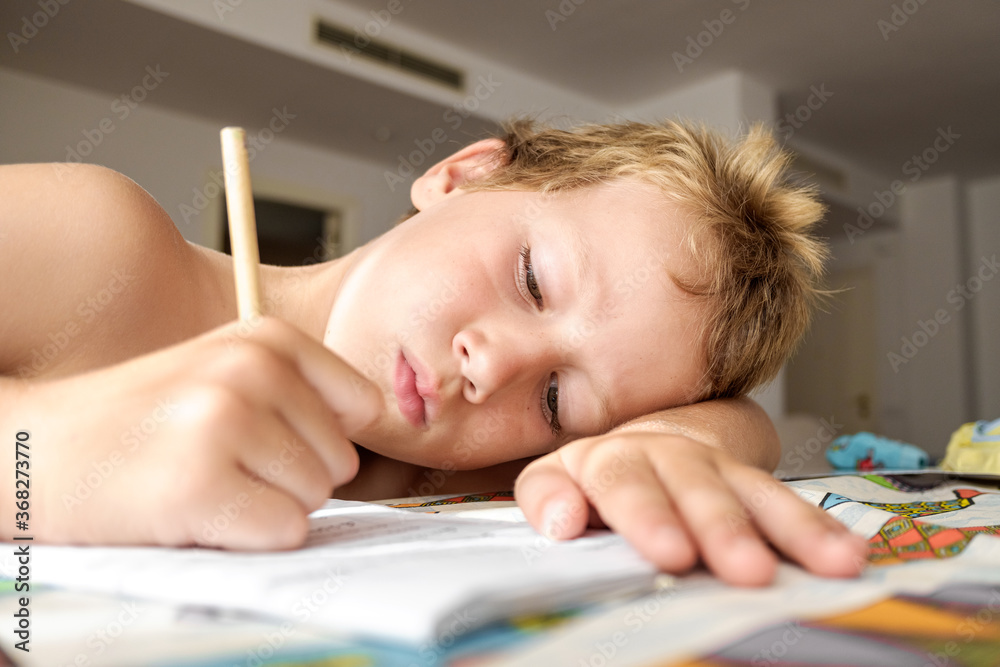 Detail of a tired and boring boy in summer while I finish his homework writing something repeated in his notebook. Detail of a tired and boring boy in summer while I finish his homework writing something repeated in his notebook.