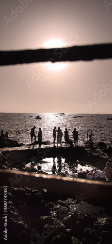 19:9 Format, Beach day with people talking and enjoying the sunny day, rocks, in sunset, volcano beach in Tenerife. 