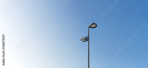 Wide format, Street light metal pole with two lamp on it, blue background , minimalist. 