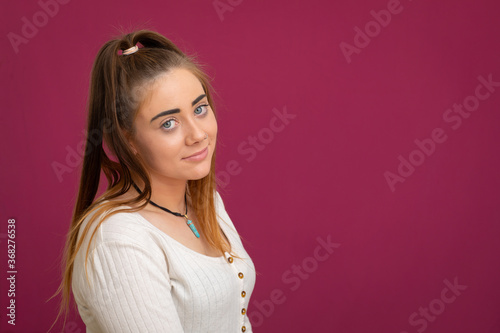 teenage girl looking resignedly at camera on magenta background photo