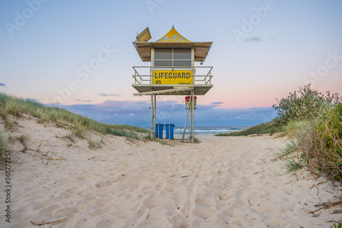 Looking up at a deserted lifeguards tower on a sandy track at twilight photo