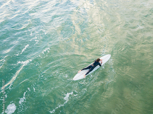 Aerial view of a lone surfer paddling a board on the ocean photo