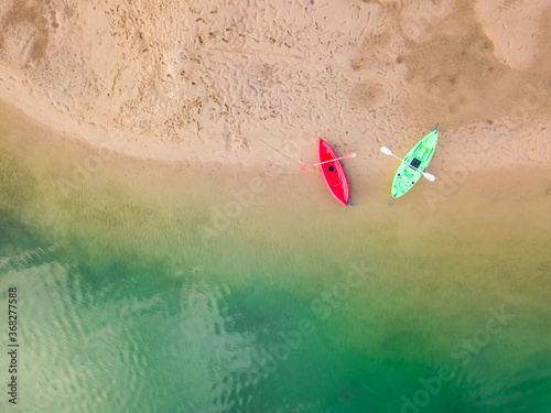 Looking down on two empty kayaks sitting on the edge of a river photo