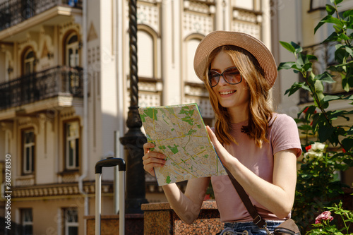 Beautiful Young Woman tourist Pleasant with city map and suitcase in the City Center