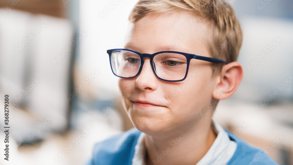 Portrait of a Cute Little Boy Wearing Glasses, Sitting at his School Desk, Smiles Happily. Smart Little Boy with Charming Smile Sitting in the Classroom. Close-up Portrait Shot Portrait of a Cute Little Boy Wearing Glasses, Sitting at his School Desk, Smiles Happily. Smart Little Boy with Charming Smile Sitting in the Classroom. Close-up Portrait Shot