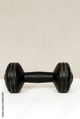 single black workout dumbbell isolated on white and grey background..