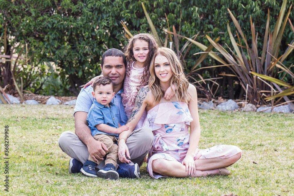Mixed race aboriginal and caucasian family of four sitting together in garden 스톡 사진 Adobe Stock