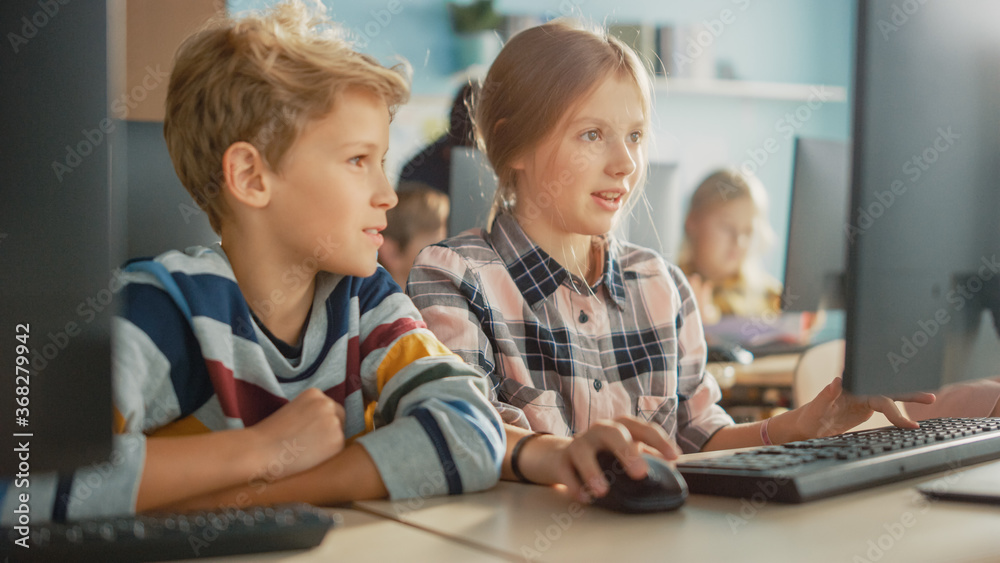 Elementary School Computer Science Classroom: Portrait of Smart Girl and Boy Talking while using Personal Computer, Learning Informatics, Internet Safety, Programming Language for Software Coding Elementary School Computer Science Classroom: Portrait of Smart Girl and Boy Talking while using Personal Computer, Learning Informatics, Internet Safety, Programming Language for Software Coding