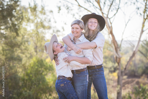 Brother and sister hugging mum laughing on farm in drought