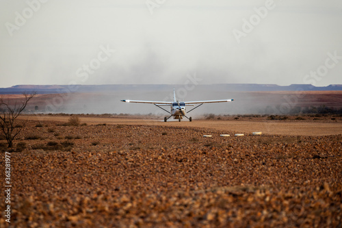 small plane landing on dirt airstrip