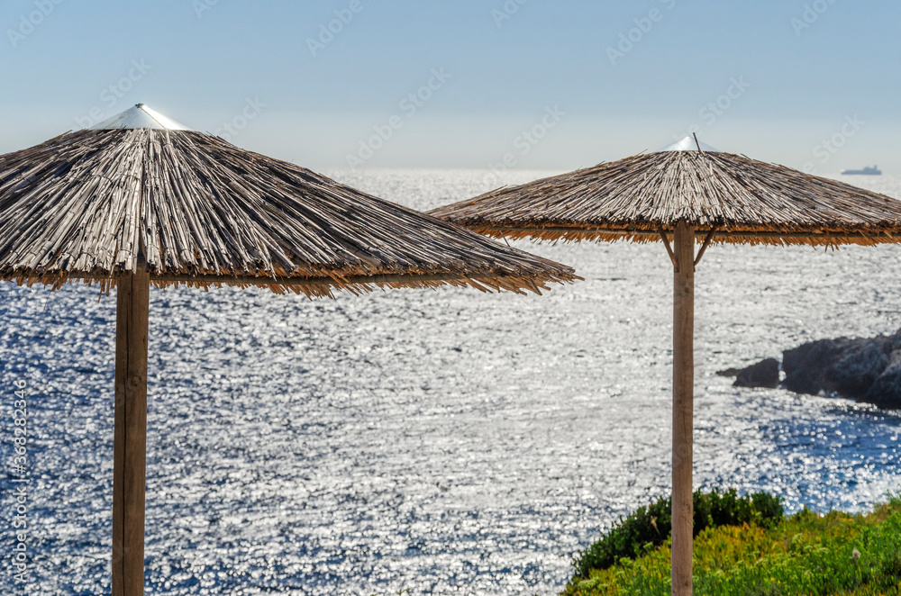 Straw beach umbrellas and sunbeds on the west coast of Zakynthos island in Greece