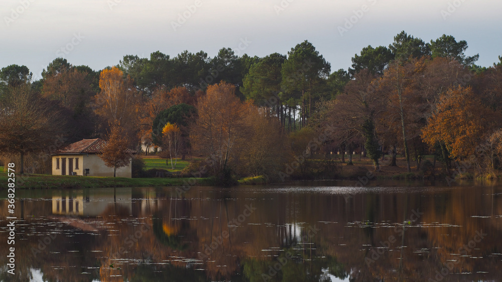 Obraz premium Lac paisible en automne, avec vue sur une maison abandonnée