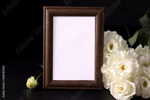 mockup of empty mourning frame next to white flowers. death and sorrow concept