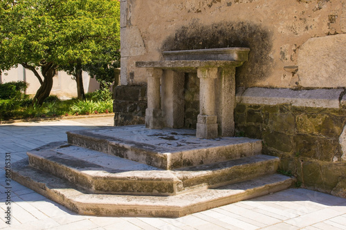 An historic stone altar next to the bell tower of Saint Vitus parish church in Podnanos, a village in the upper Vipava Valley in the Municipality of Vipava in the Primorska region of Slovenia. The chu photo