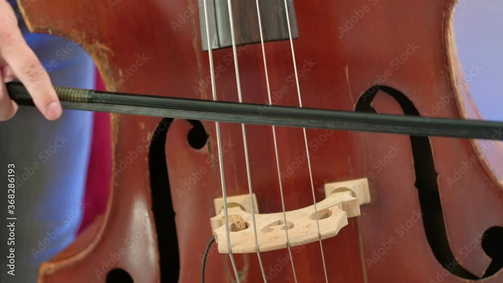 Men is playing double bass with bow. close up. Man musician performing bow technique. contrabass rhythm at classical concert. Acoustic bass instrument Men is playing double bass with bow. close up. Man musician performing bow technique. contrabass rhythm at classical concert. Acoustic bass instrument
