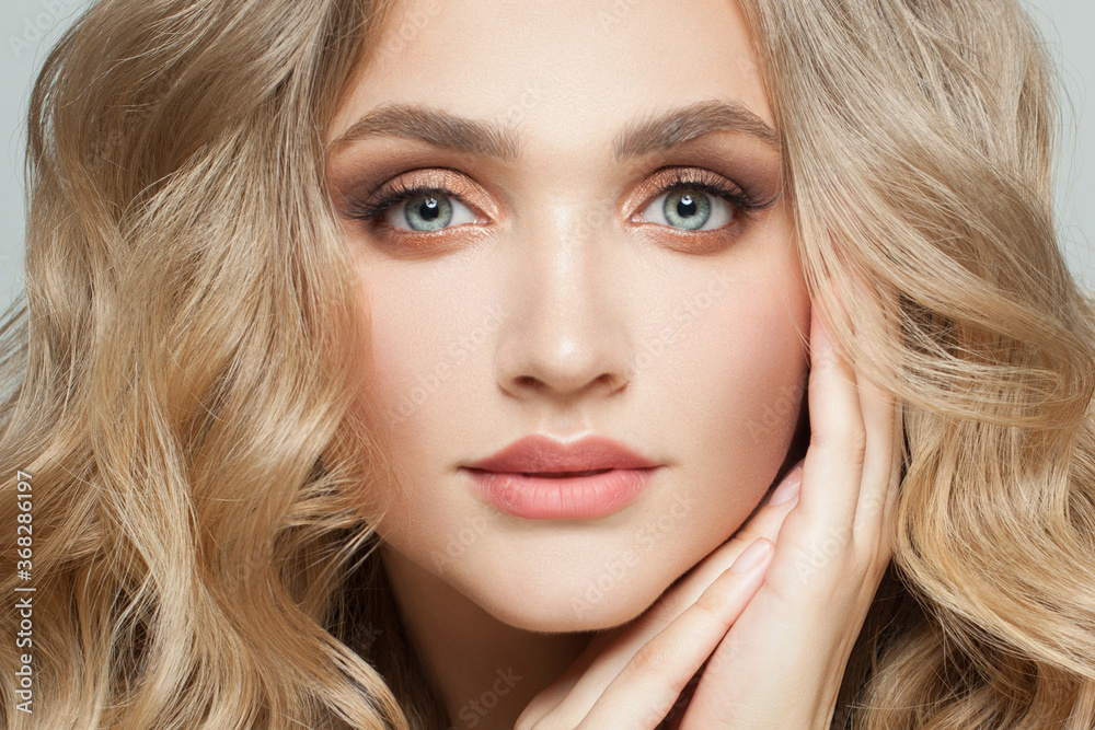Beautiful woman face. Perfect female with long healthy blonde curly hairstyle and natural makeup close up Beautiful woman face. Perfect female with long healthy blonde curly hairstyle and natural makeup close up