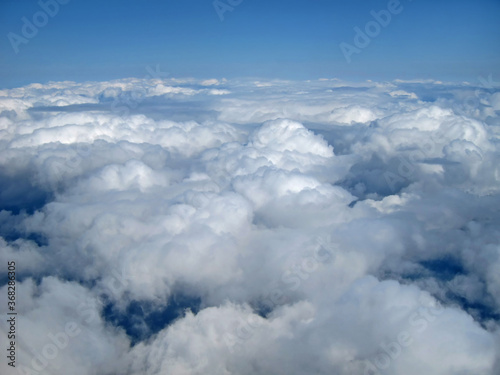 Fototapeta Naklejka Na Ścianę i Meble -  White,puffy clouds and blue sky above the clouds from a mid air perspective.  Great for environment, space, climate, ecology, air and flying concepts.