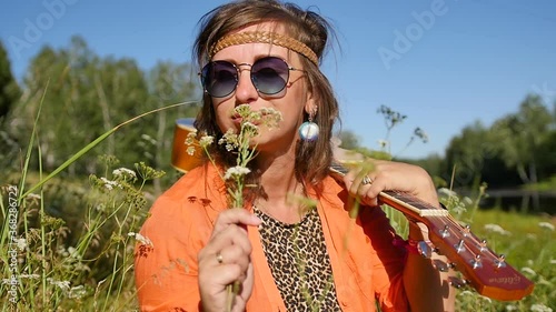 Slow motion. nature, summer vacation, vacation and people concept - happy smiling woman in sunglasses stands with a guitar on her shoulder. photo