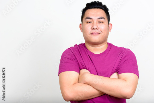 Portrait of young handsome overweight Asian man with arms crossed