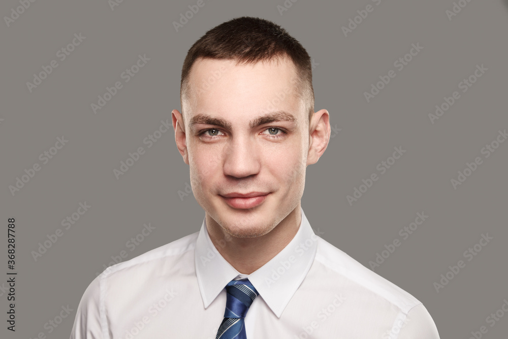 Handsome confident young caucasian man in white shirt and necktie standing over gray background Handsome confident young caucasian man in white shirt and necktie standing over gray background