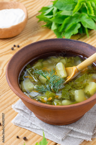 Traditional rustic green soup in a clay plate on a wooden background