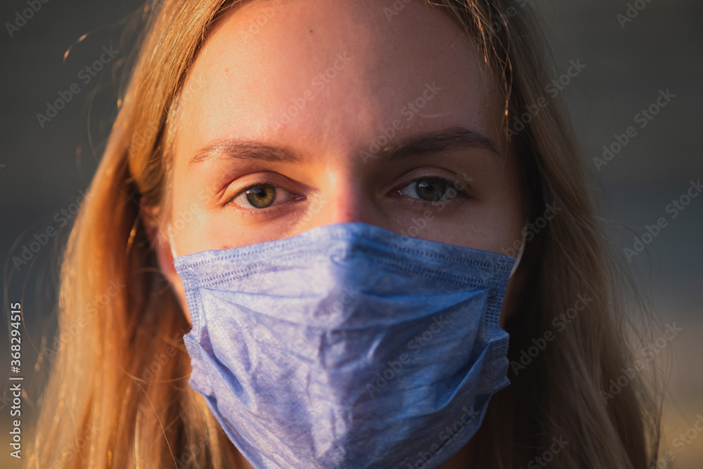 Close-up portrait of a woman wearing a mask outdoors. Public health, safe lifestyle, post-pandemic covid-19 concept Close-up portrait of a woman wearing a mask outdoors. Public health, safe lifestyle, post-pandemic covid-19 concept