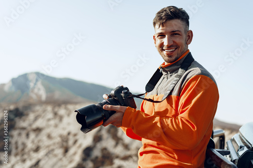 Young man traveler taking photos of mountains with professional camera