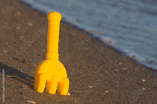 Children's toy in the sand by the ocean. Surf waves and soft light. Conceptual photo. photo