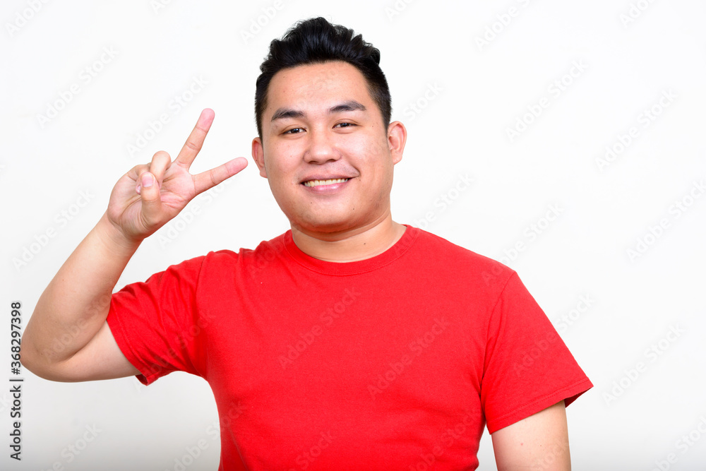Portrait of happy young handsome overweight Asian man Portrait of happy young handsome overweight Asian man