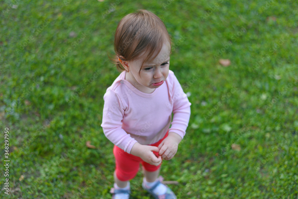 Adorable happy baby girl having fun in park grass, playing in the summer park. Adorable happy baby girl having fun in park grass, playing in the summer park.