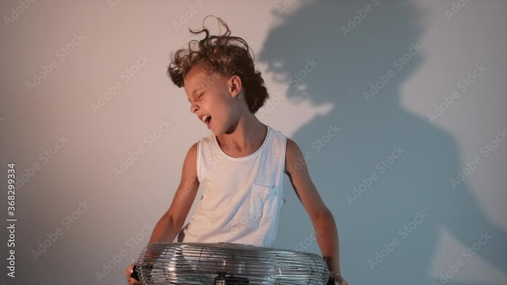 Boy holding a running fan while screaming