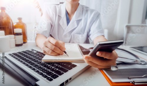 Medical technology concept The doctor works with mobile phones, headphones and tablets. Digital laptop Pressing the calculator in the modern office at the hospital in the morning