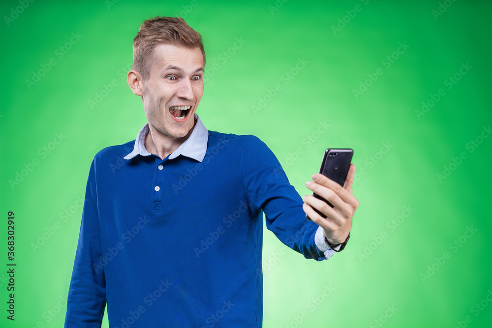 A man with great surprise and delight looks at the phone, the proposed tariff, the proposed service A man with great surprise and delight looks at the phone, the proposed tariff, the proposed service