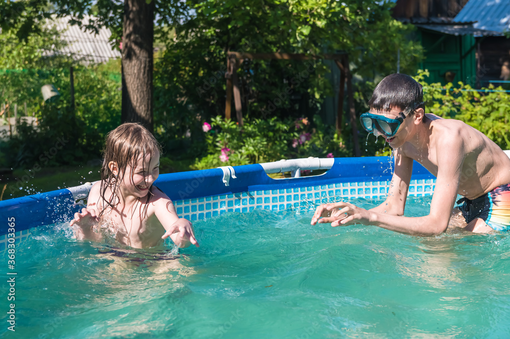 brother and sister play in the summer in the pool