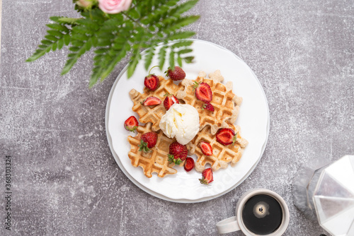 Viennese waffles with ice-cream and strawberries with cup of coffee. Top view. Grey background.