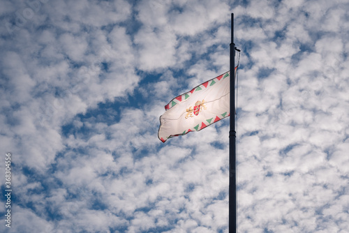 The Hungarian flag unfurled against a cloudy blue sky.