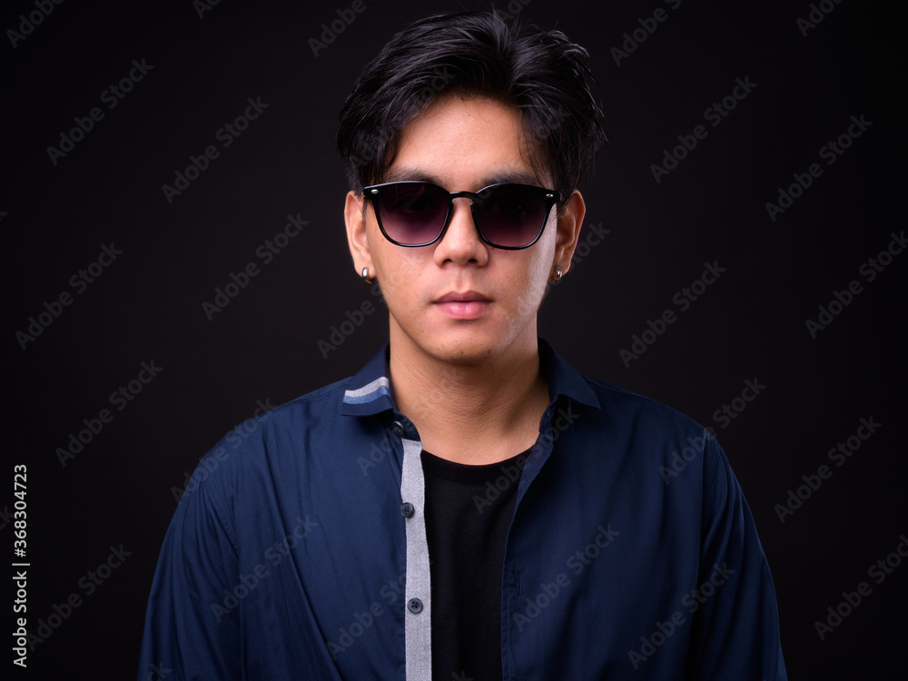 Obraz premium Young handsome Asian man against black background