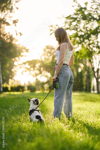 Young woman and french bulldog in park.
