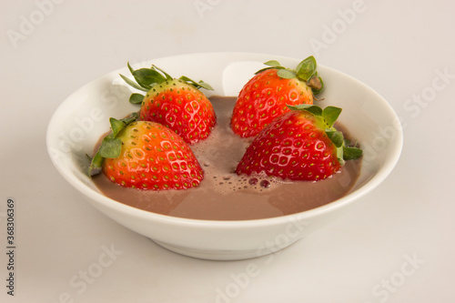 Fresh red strawberries in a bowl with chocolate cream.