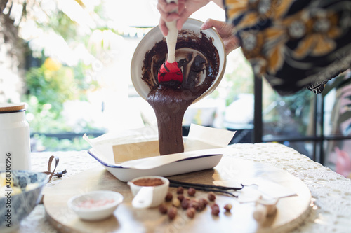 Woman pouring brownie batter into baking dish in kitchen photo