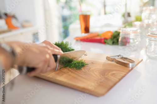 Woman cutting fresh dill on cutting board photo