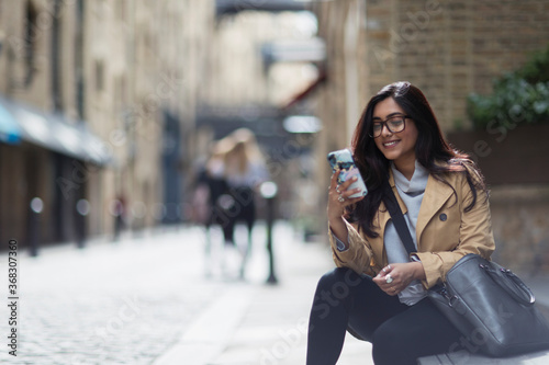 Smiling businesswoman using smart phone on city sidewalk photo