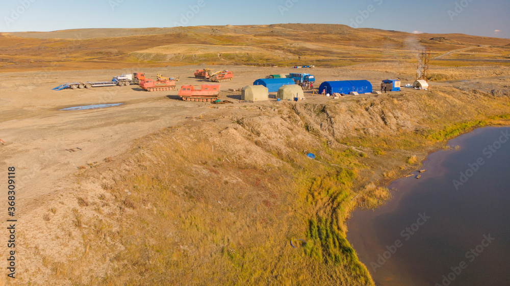 Field geological camp, in the middle of the tundra, with tents and drilling rigs