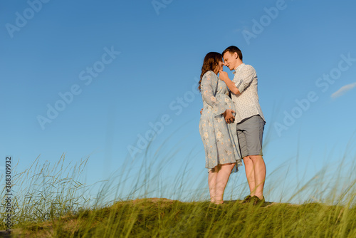 Happy young couple kissing on top of a mountain  with clear sky in the background. Happy family