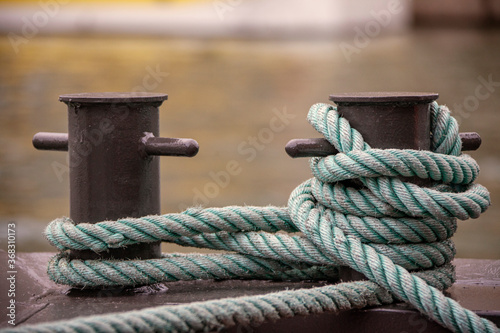 Nautical tie downs secure moored boats on a wharf pier.
