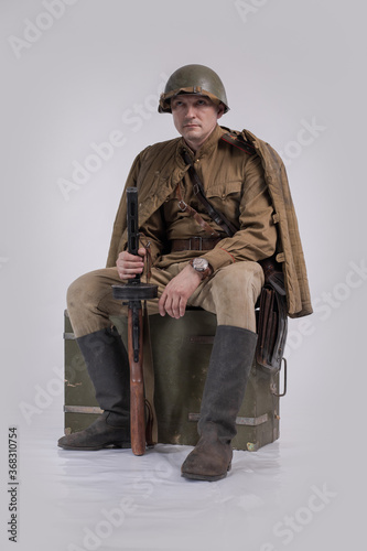 Male actor in the uniform of an officer and a helmet of the Soviet Army during World War II with a rifle in his hands photo