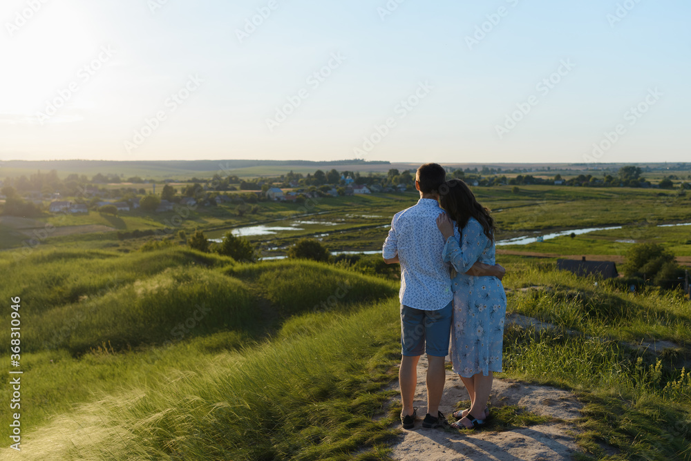 Happy young couple kissing on top of a mountain, with clear sky in the background. Happy family